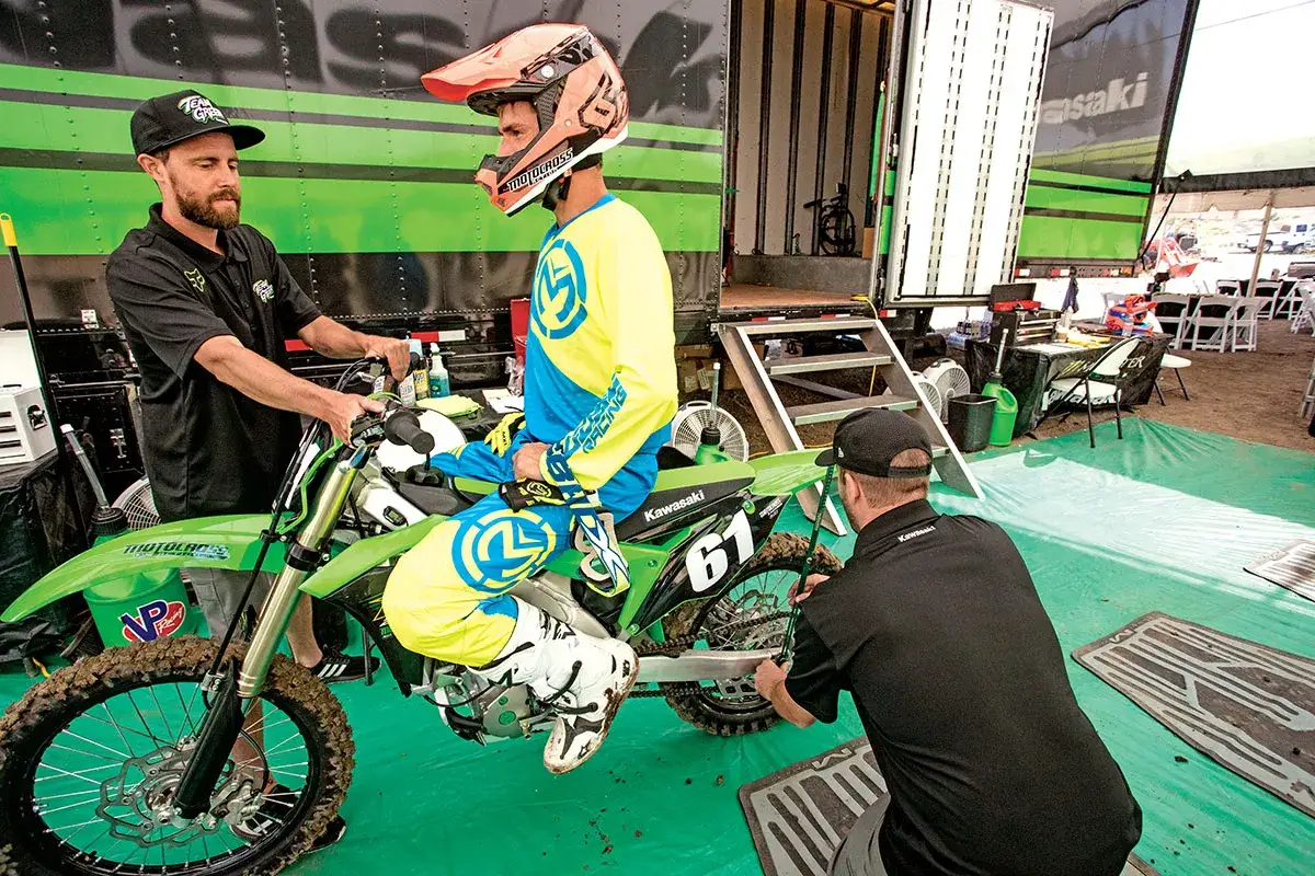 Mechanik sprawdza ustawienie sag w motocyklu, pomagając zawodnikowi w przygotowaniach do wyścigu.