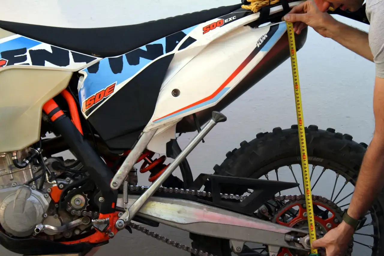 Mężczyzna mierzy tylne zawieszenie motocykla KTM za pomocą miarki.