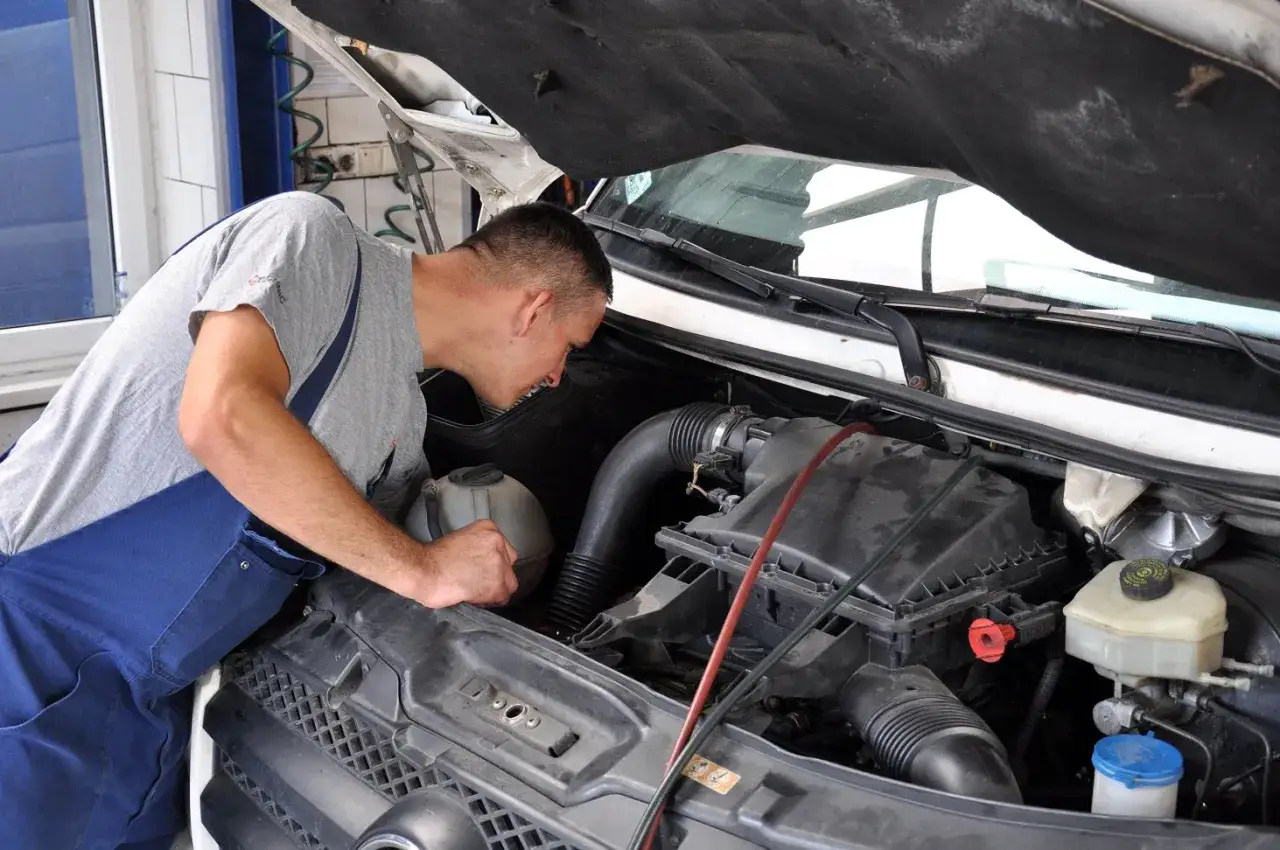 Mechanik bada silnik, szukając objawów pękniętej głowicy.