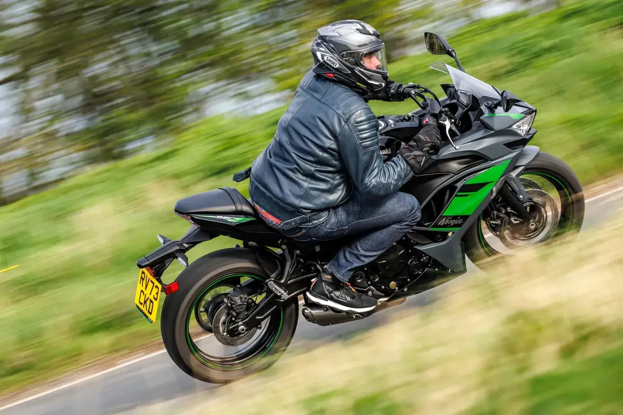 Motocyklista na Kawasaki Ninja 650, z zielonymi akcentami, pędzi po drodze. Poznaj kawasaki ninja 650 dane techniczne.