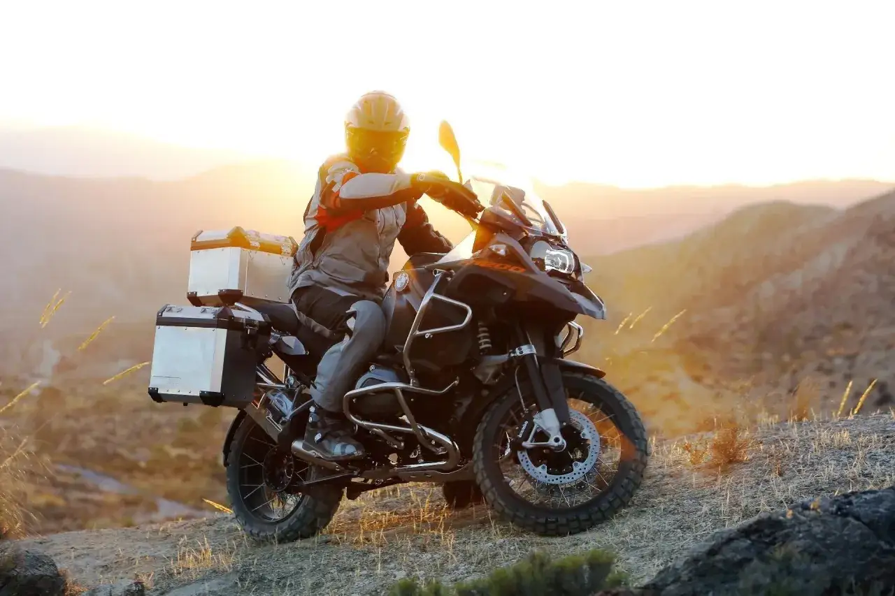 Motocyklista na BMW GS 1200 z kuframi, gotowy na przygodę. Waga motocykla nie przeszkadza w pokonywaniu trudnego terenu.