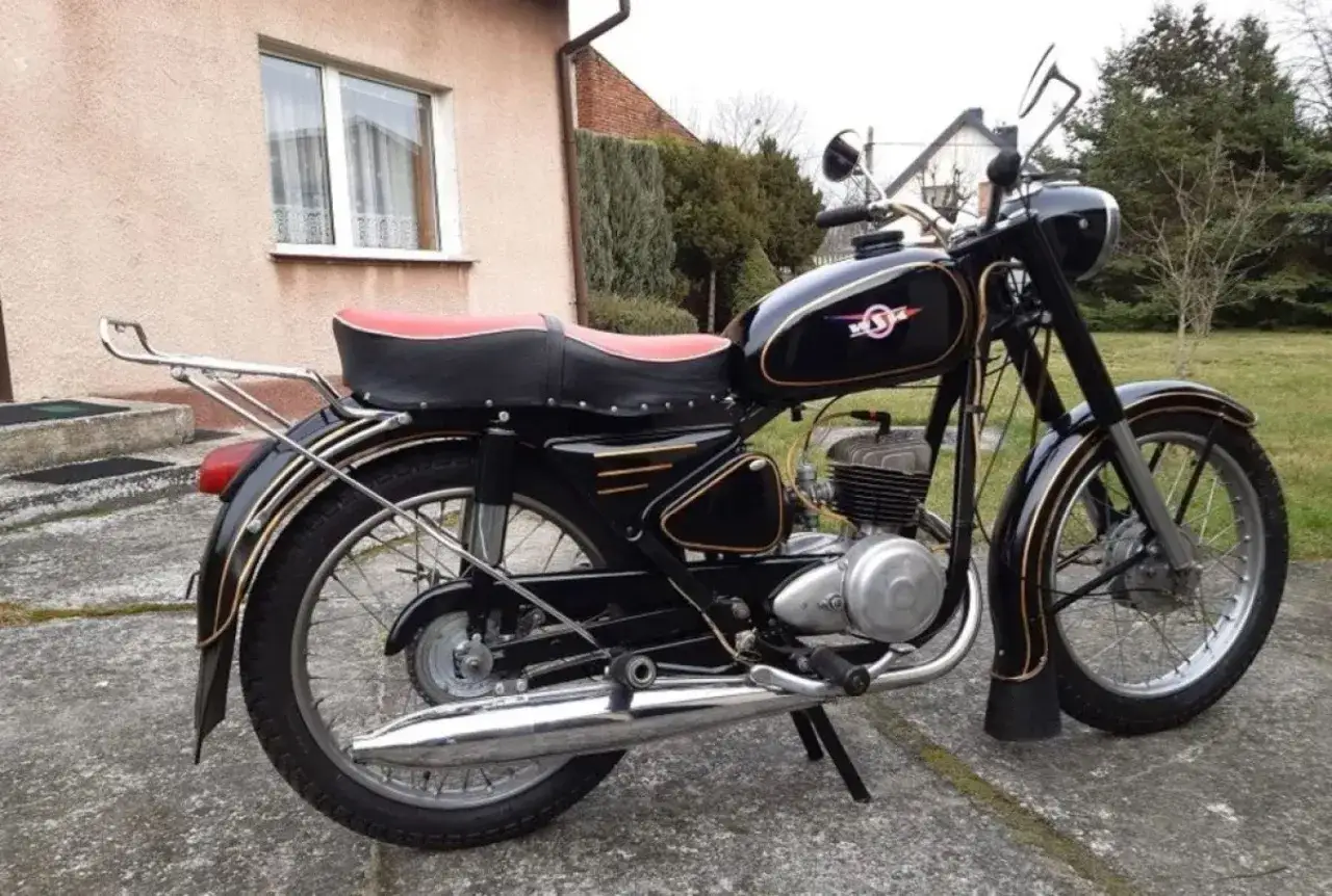 Czarny motocykl z PRL-u, z czerwoną kanapą i złotymi wstawkami. Klasyk polskich dróg.