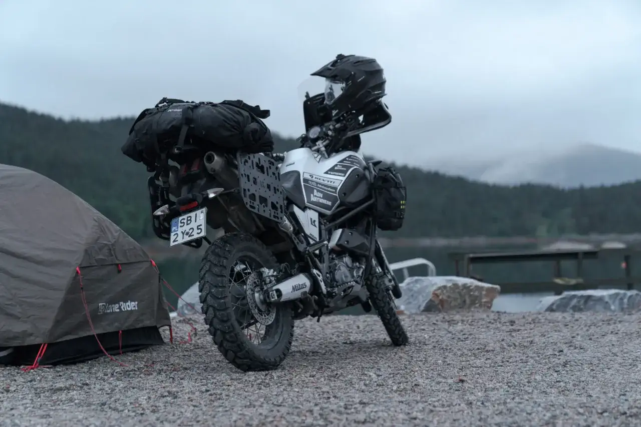 Motocykl turystyczny z sakwami i kaskiem obok namiotu. Idealny zestaw, jaki namiot na motocykl sprawdzi się w podróży?