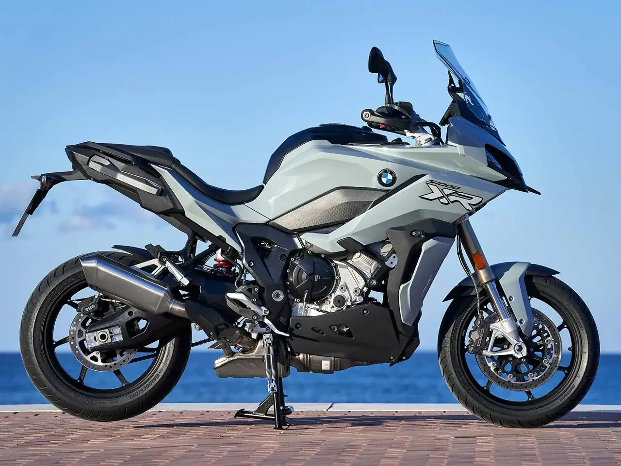 Szary motocykl BMW S1000XR na tle morza. Poznaj jego dane techniczne i możliwości.
