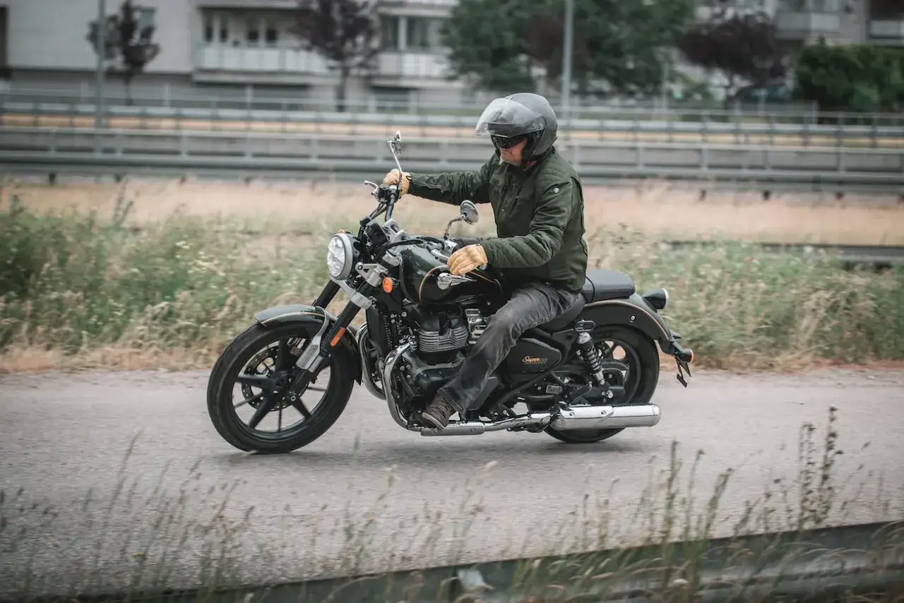 Mężczyzna w kasku i rękawiczkach jedzie na stylowym motocyklu Royal Enfield Super Meteor 650.