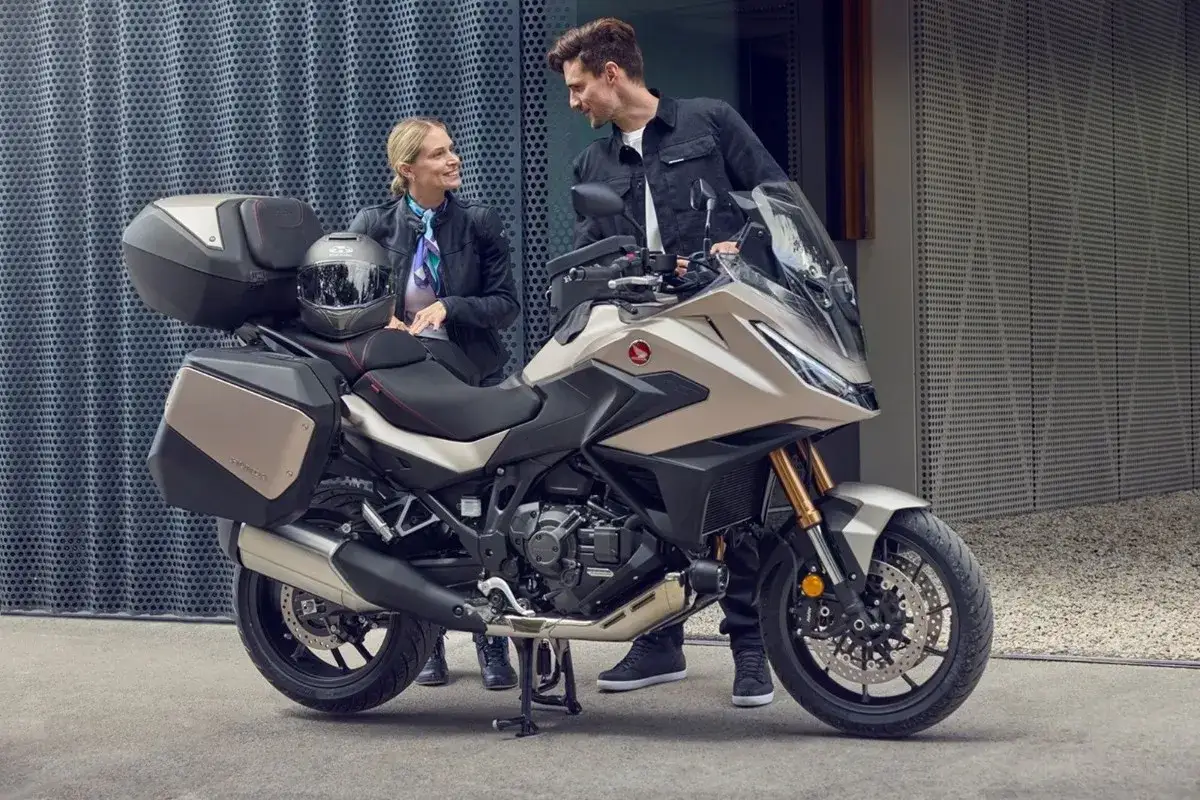 Para zwiedzająca motocykle z automatyczną skrzynią biegów. Nowoczesny turystyczny jednoślad z kuframi.