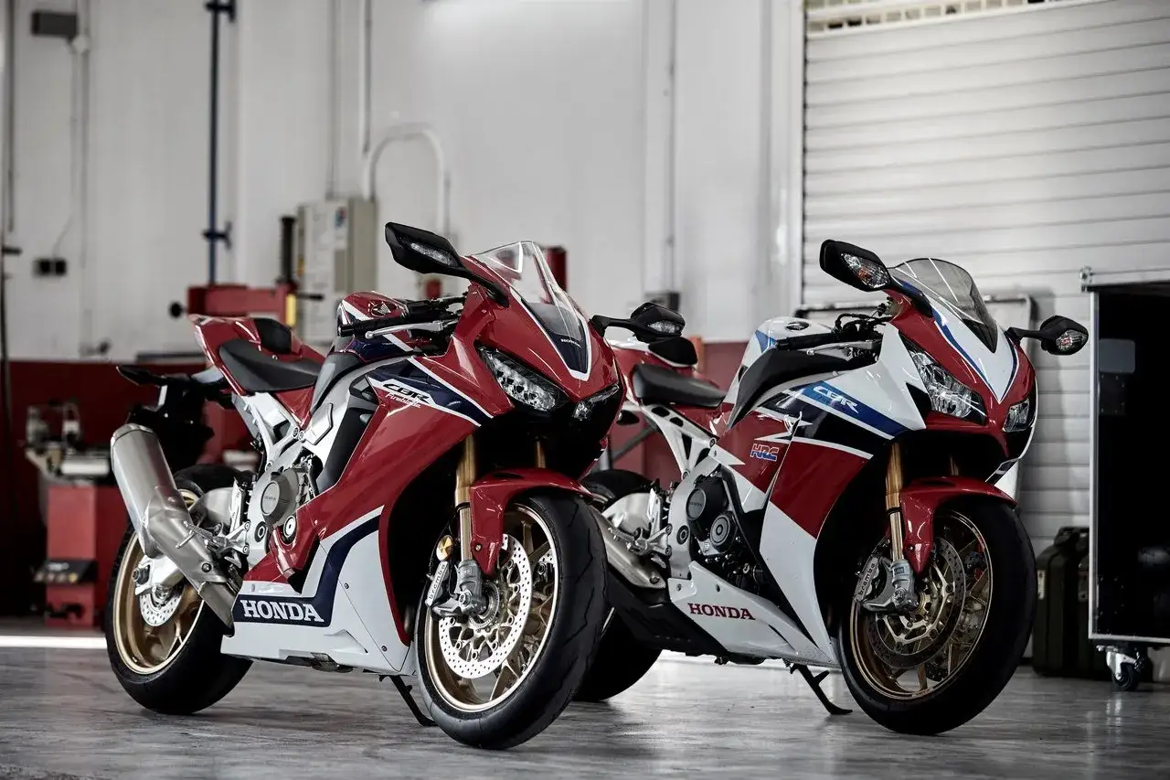 Dwa sportowe motocykle Honda seria CBR w czerwono-biało-niebieskich barwach stoją obok siebie w garażu.