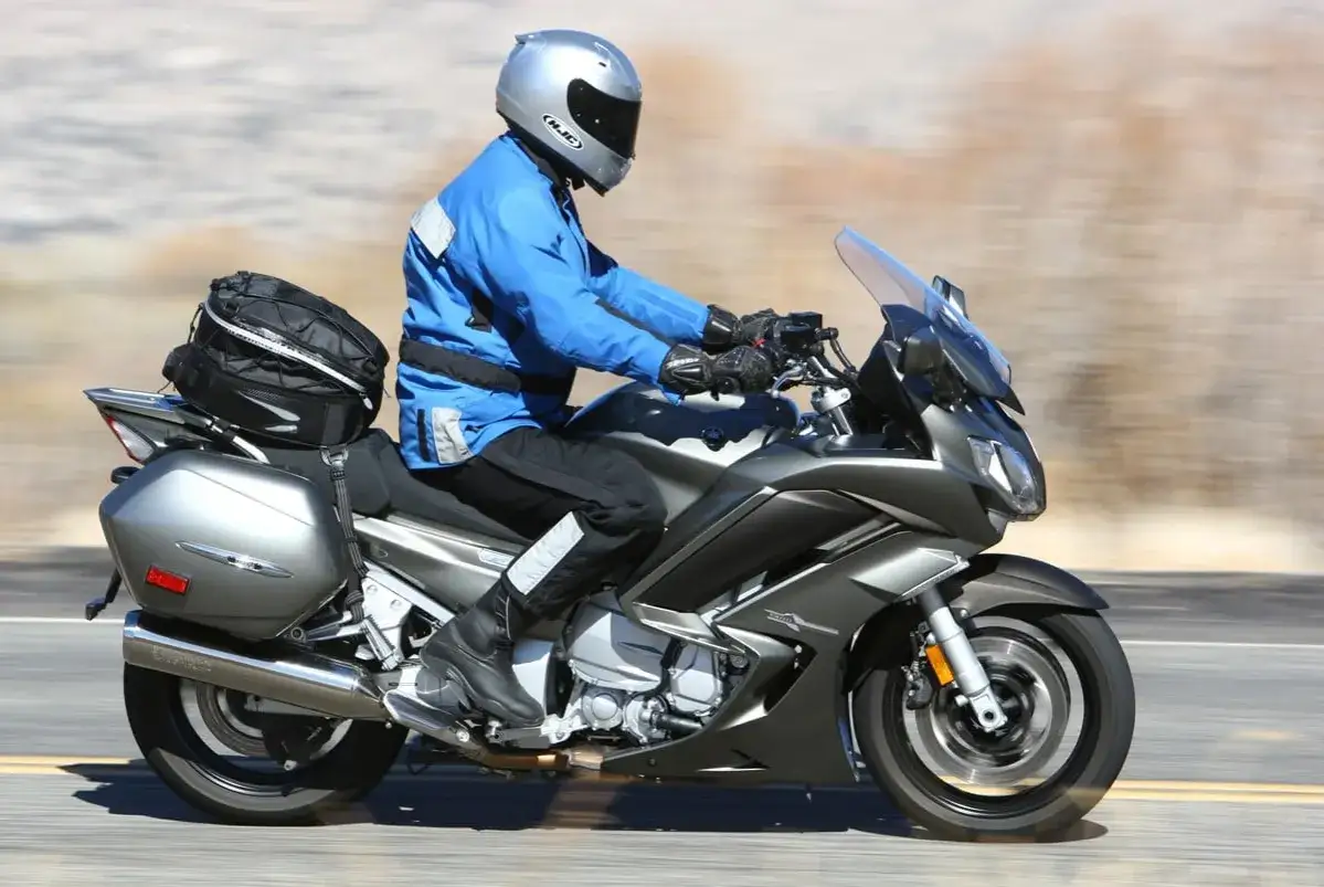 Motocyklista na szarym Yamaha FJR 1300, z bagażem, pokonuje drogę. Wady tego modelu mogą dotyczyć komfortu na długich trasach.