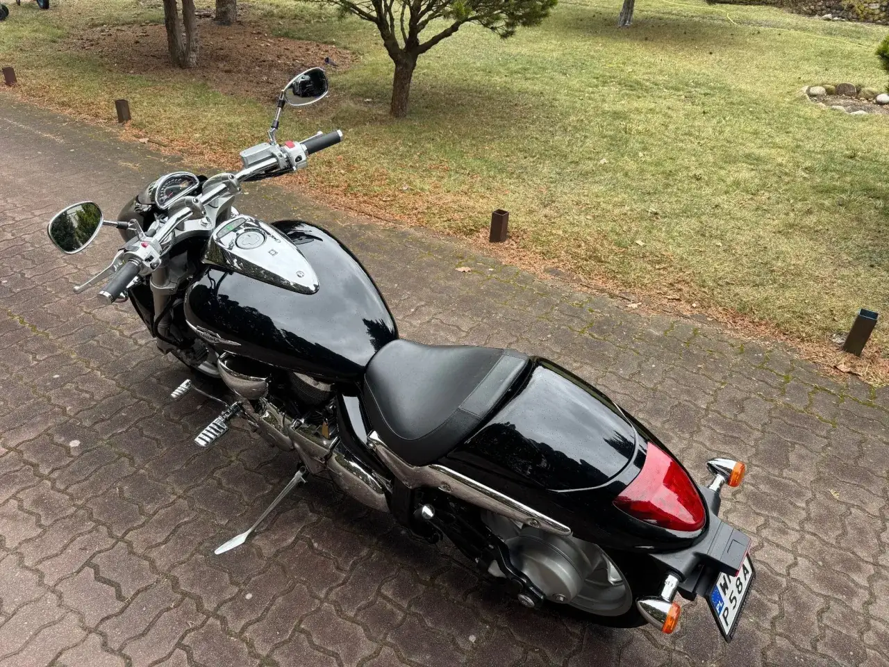 Czarny motocykl Suzuki Intruder 1500 na podjeździe. Wady tego modelu to m.in. wysokie spalanie i ograniczona zwrotność.