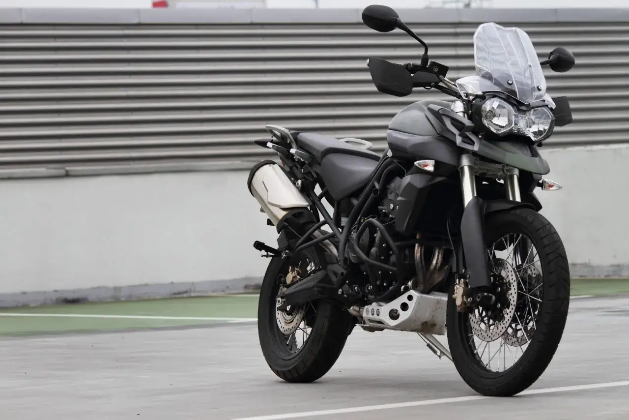 Triumph Tiger 800 XC dane techniczne: szary motocykl adventure z czarnym siedzeniem i dużą szybą stoi na betonowym placu.