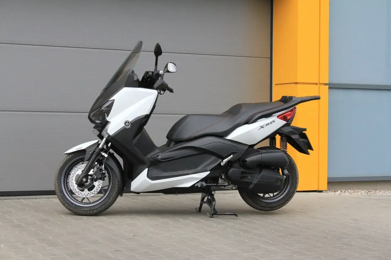 Biały skuter Yamaha X-MAX 125, gotowy do jazdy. Jego prędkość maksymalna pozwala na sprawne poruszanie się po mieście.