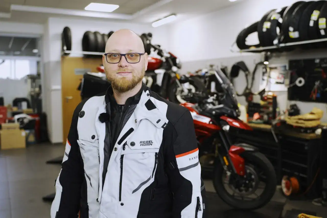 Mężczyzna w okularach prezentuje profesjonalne ubranie na motor turystyczny.