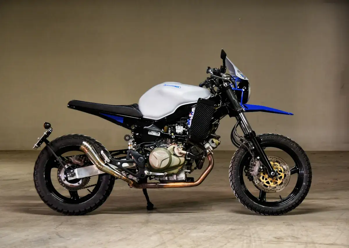 Zmodyfikowany Honda Varadero XL 1000 w stylu scrambler, z biało-niebieskim malowaniem i wydechem.