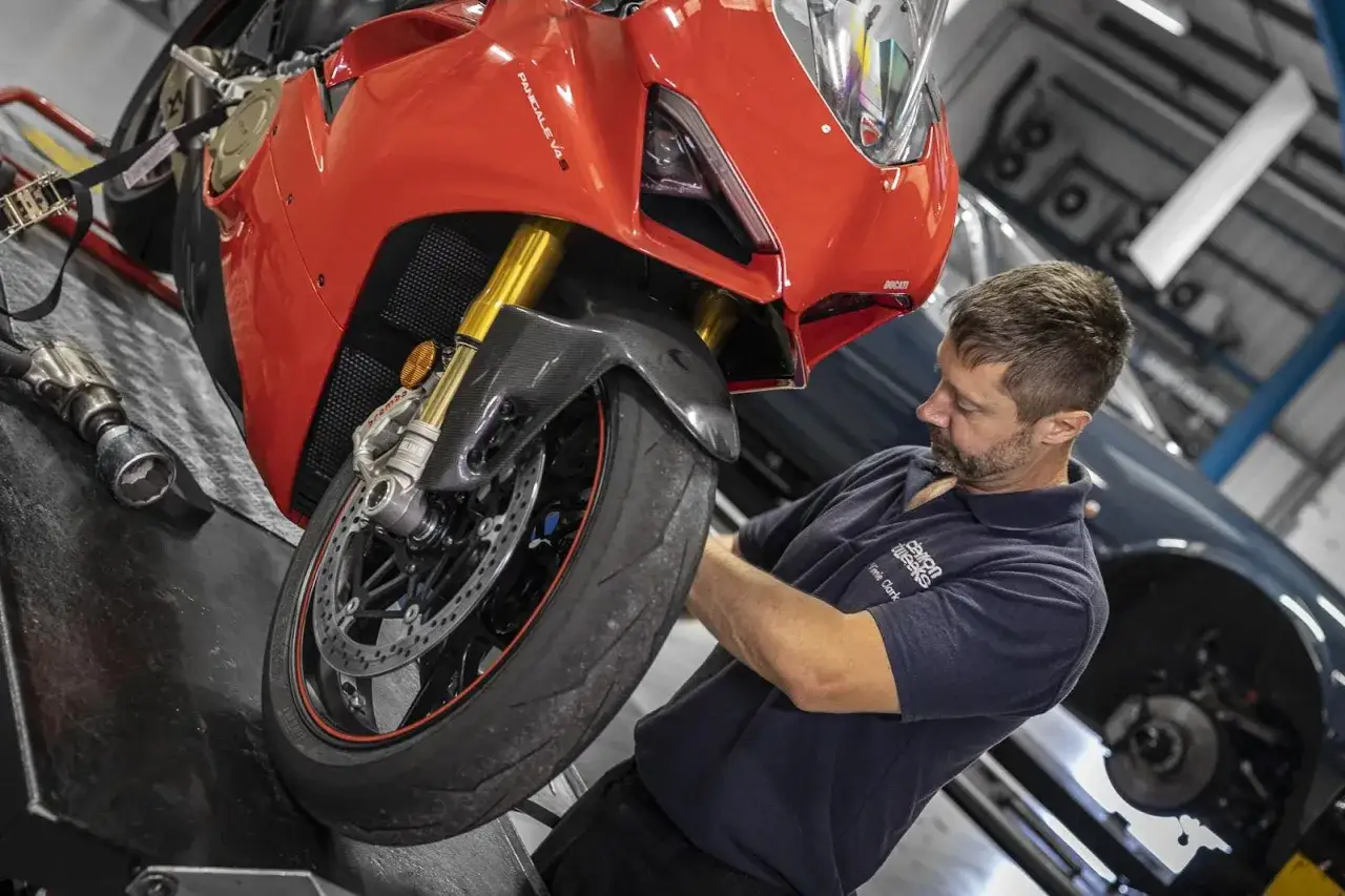 Mechanik dokonuje wymiany opon motocyklowych w czerwonym Ducati.