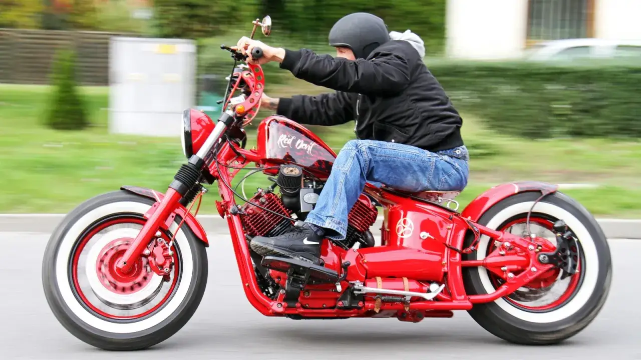 Czerwony motocykl Yamaha Drag Star 1100 z białymi oponami, w ruchu. Dane techniczne tego customa robią wrażenie.