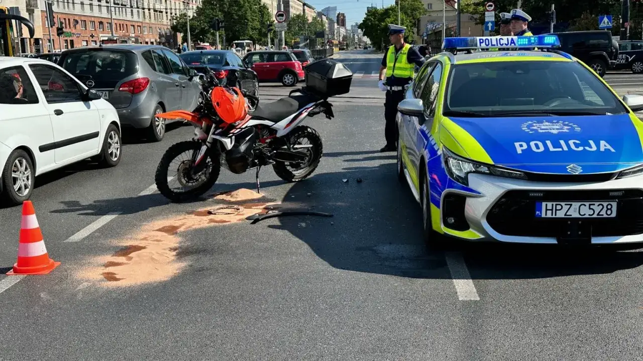 Motocykl leży na ziemi obok radiowozu. Wygląda na to, że kierowca próbował wykonać jazdę na jednym kole, co skończyło się mandatem i wypadkiem.