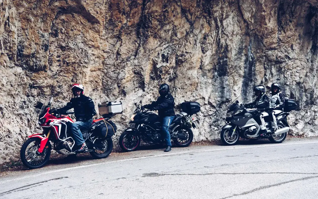 Motocykliści na tle skalnej ściany przy drodze Strada della Forra.