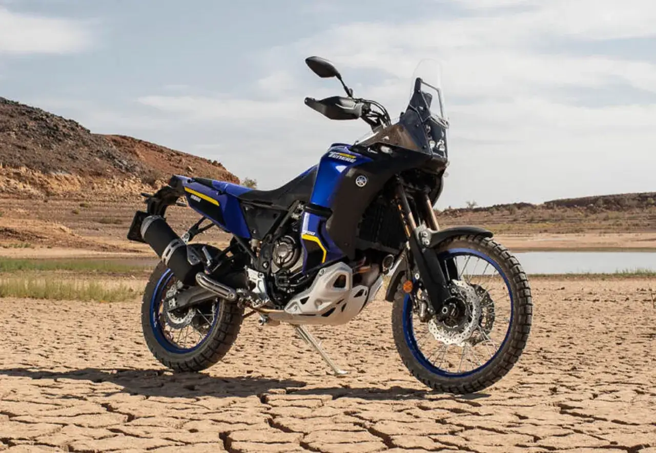 Niebiesko-czarny motocykl Yamaha Ténéré 700 World Raid gotowy na przygodę na pustynnym, spękanym terenie.