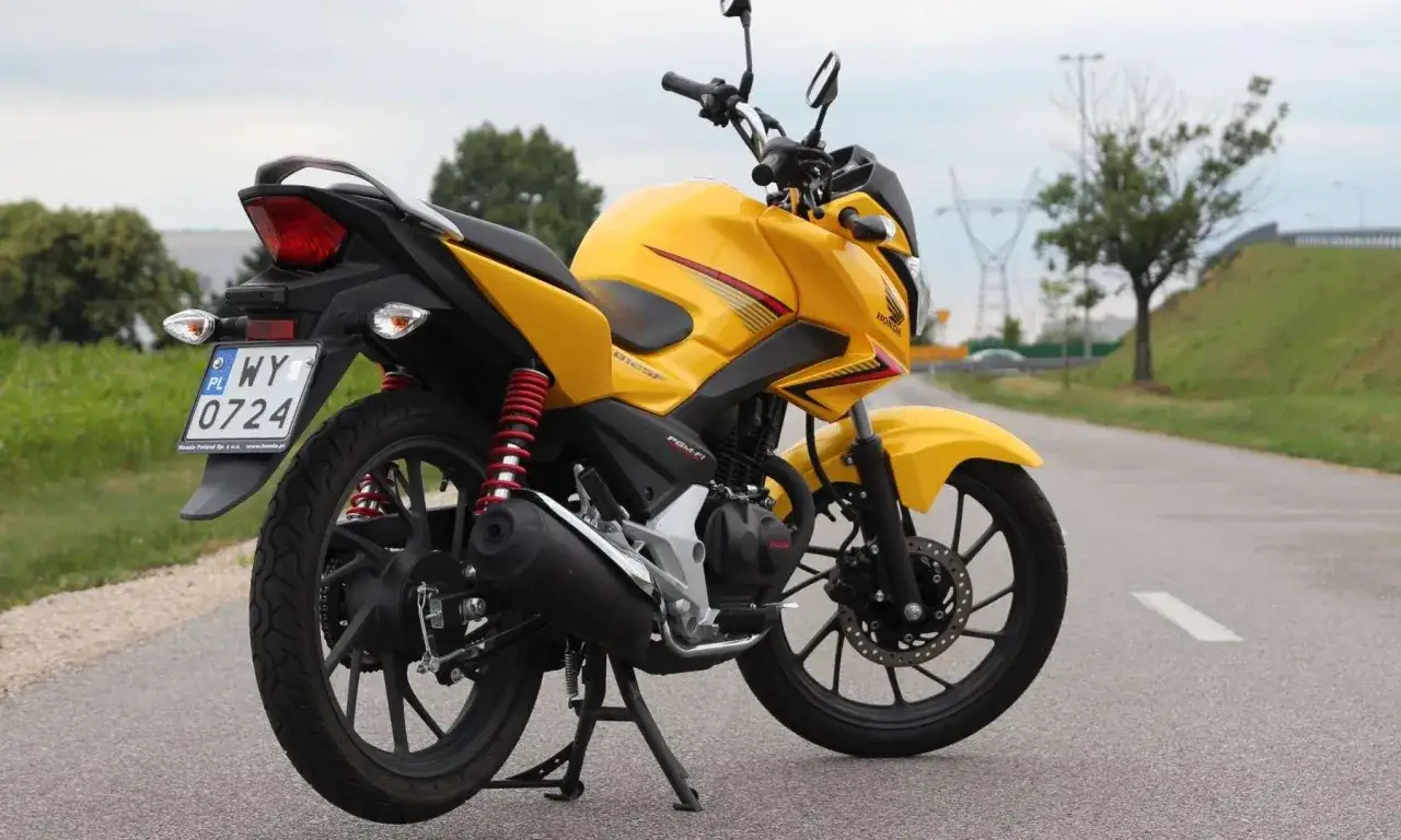 Żółty motocykl Honda CBF 125 na drodze. Poznaj honda cbf 125 dane techniczne i możliwości tego zwinnego sprzętu.