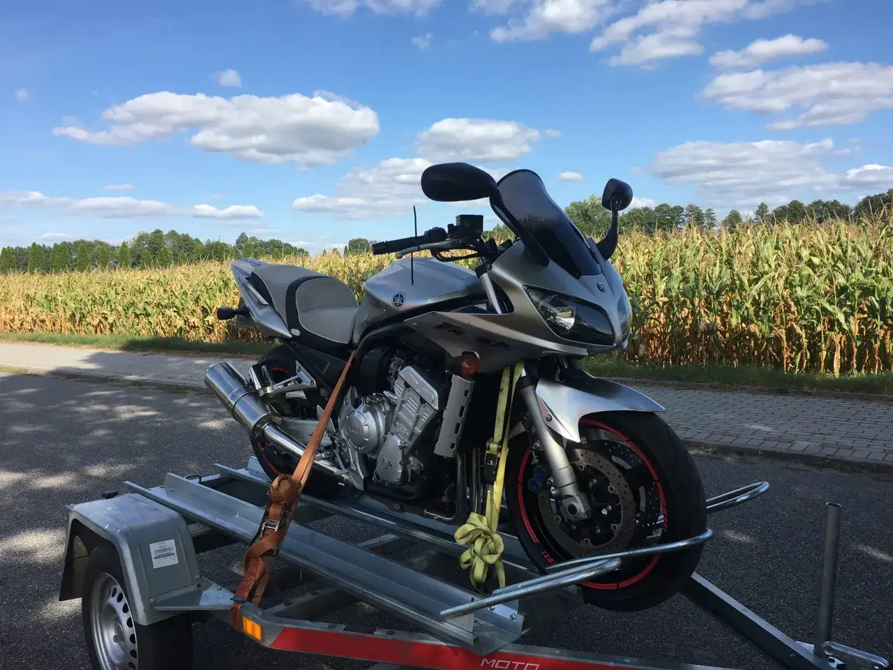 Srebrny motocykl Yamaha na przyczepce, gotowy do rejestracji. Czas na opłatę skarbową za motocykl z zagranicy.