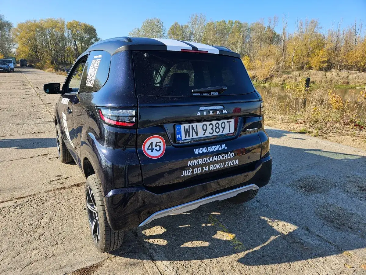 Czarny mikrosamochód Aixam z naklejką