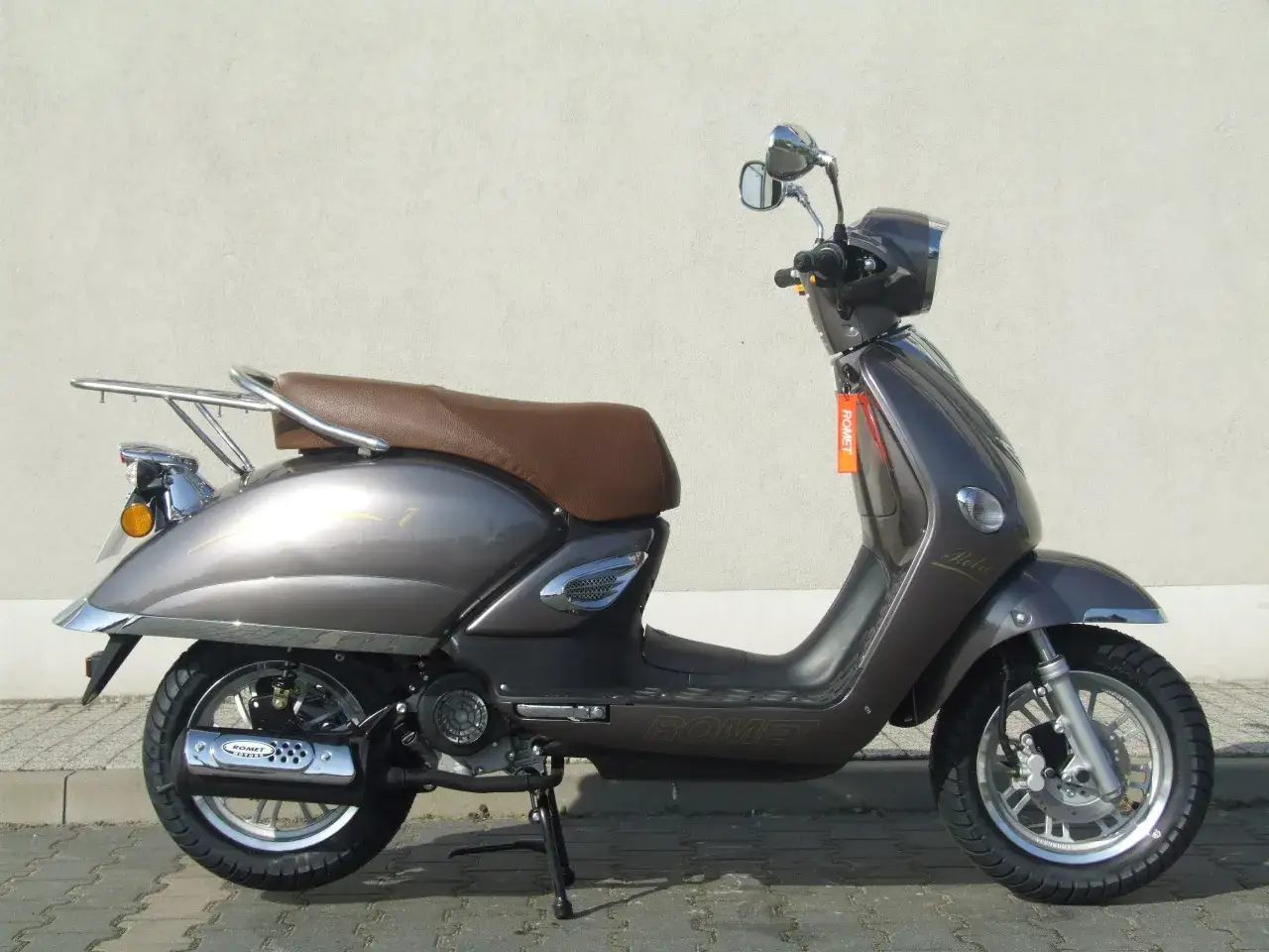 Elegancki skuter Romet Retro 7 50 w kolorze grafitowym, z brązową kanapą i chromowanymi elementami, gotowy na miejskie podróże.