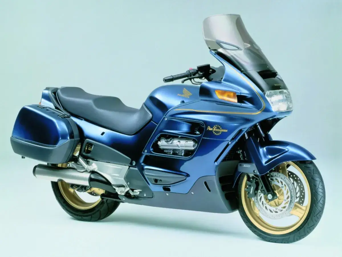 Błękitny motocykl Honda Pan European z kuframi, złote detale i wysoka szyba.