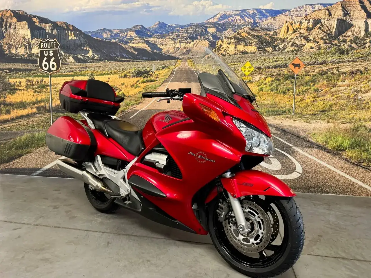 Czerwony motocykl Honda Pan European z kuframi, gotowy na podróż przez malownicze krajobrazy Route 66.