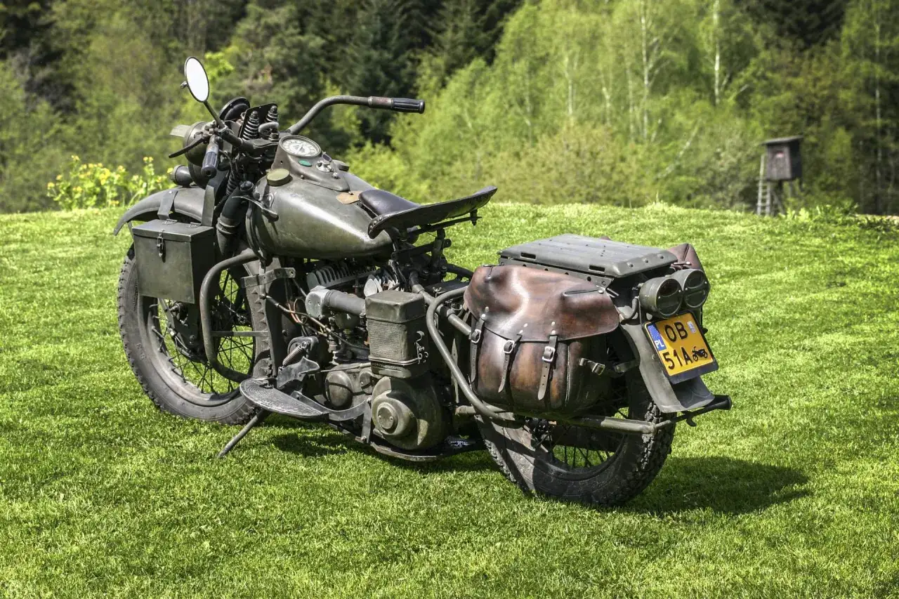 Stary, wojskowy motocykl z sakwami, gotowy do rejestracji na zabytek. Zielony lakier, skórzane detale i tablica z napisem 