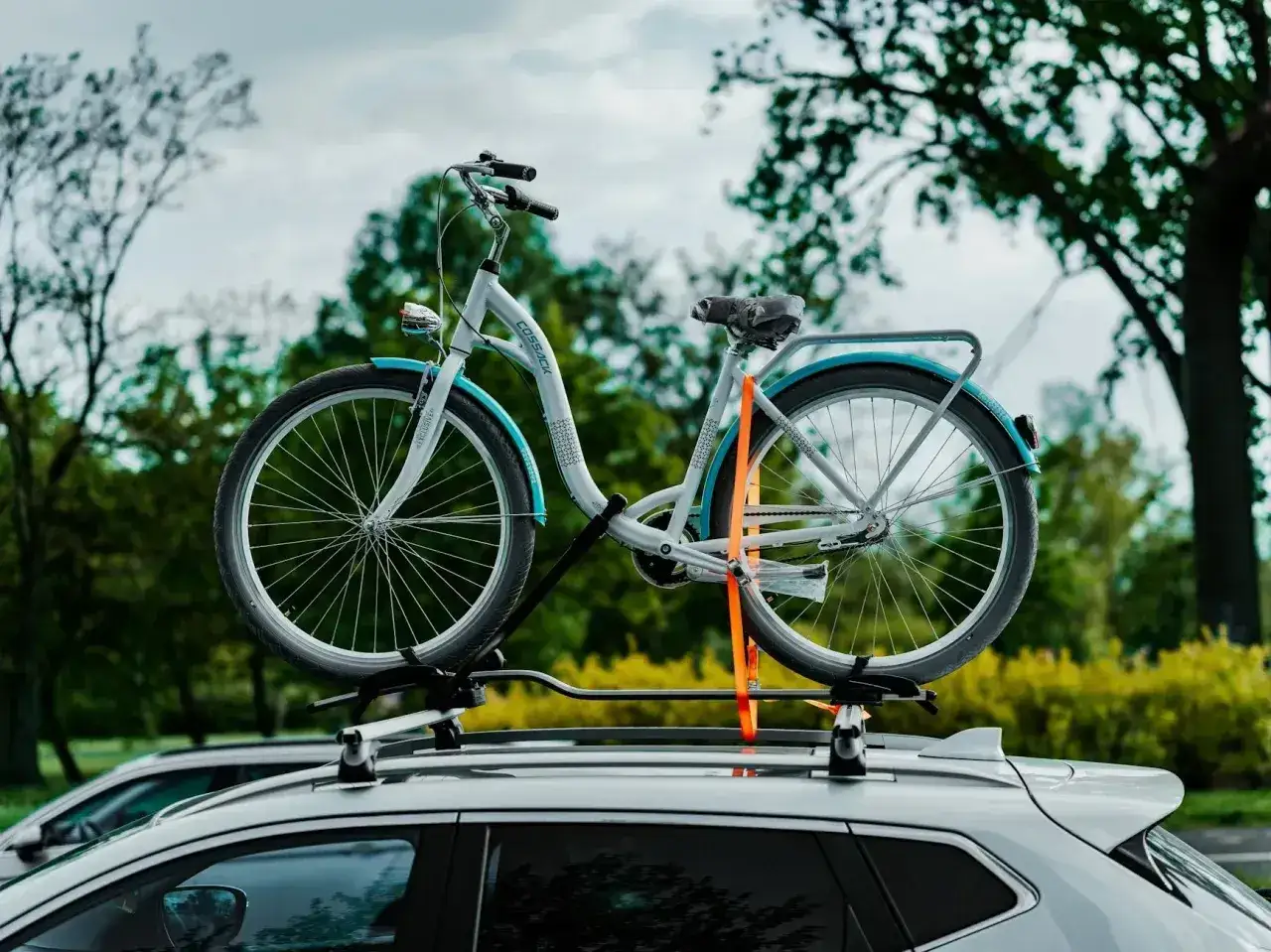 Biały rower na bagażniku dachowym samochodu. To przykład pojazdu mechanicznego, który ułatwia transport.