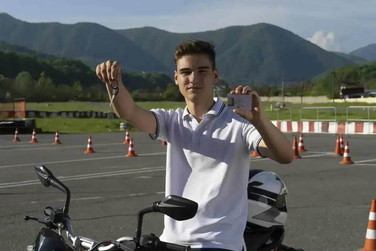 Młody mężczyzna z kluczykami i kartą motorowerową, gotowy do jazdy. Od ilu lat można uzyskać kartę motorowerową?