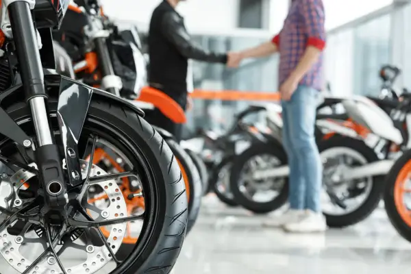 Dwóch mężczyzn ściska sobie dłonie przy motocyklach. Transakcja sprzedaży motocykla zakończona, czas pomyśleć o podatku od sprzedaży motocykla.