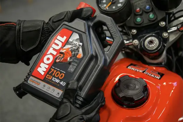 Rękawice motocyklowe trzymają olej Motul 7100 10W-40. Sprawdź, co ile wymieniać olej w motocyklu, by zapewnić mu długą żywotność.