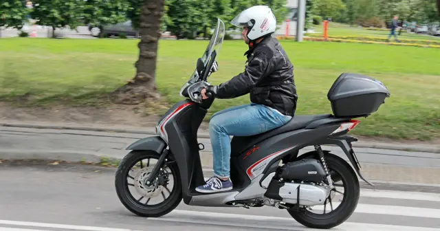 Mężczyzna w kasku jedzie na skuterze Honda SH 125. Czy są jakieś wady tego modelu?