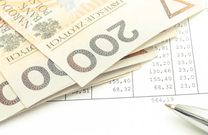 Polskie banknoty 200 zł leżą na arkuszu z wyliczeniami. Czy to podatek od kupna motocykla? Długopis wskazuje na kwotę.