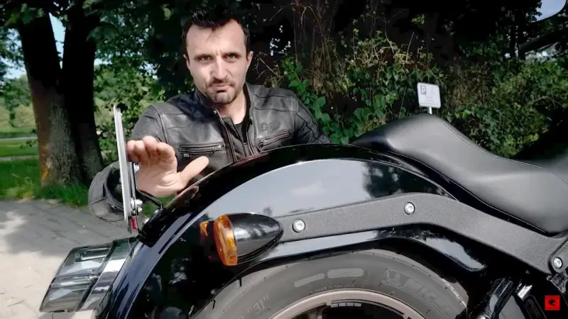 Mężczyzna pokazuje mocowanie tablicy rejestracyjnej motocykl, omawiając przepisy.
